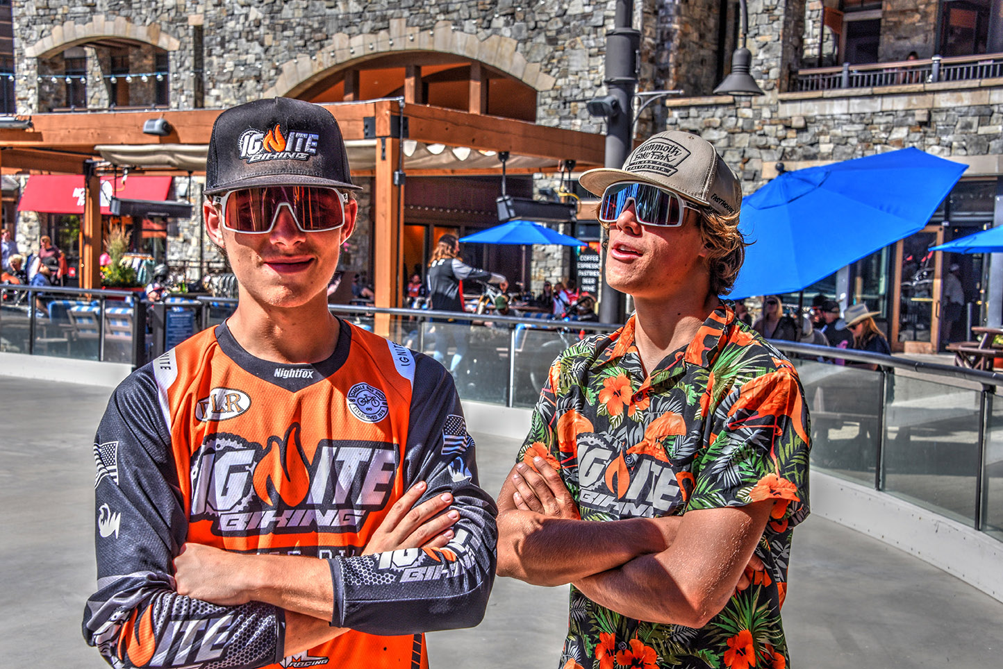 Two Ignite MTB Crew members relaxing and smiling at the finish line of the Northstar Downhill Series, wearing caps and sunglasses