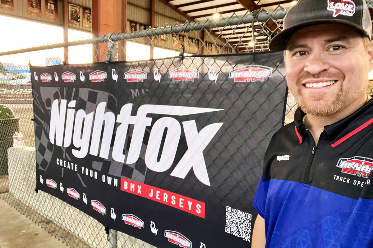 Bobby, the track operator of DeSoto BMX Track, taking a selfie with the Nightfox flag in the background, smiling proudly.