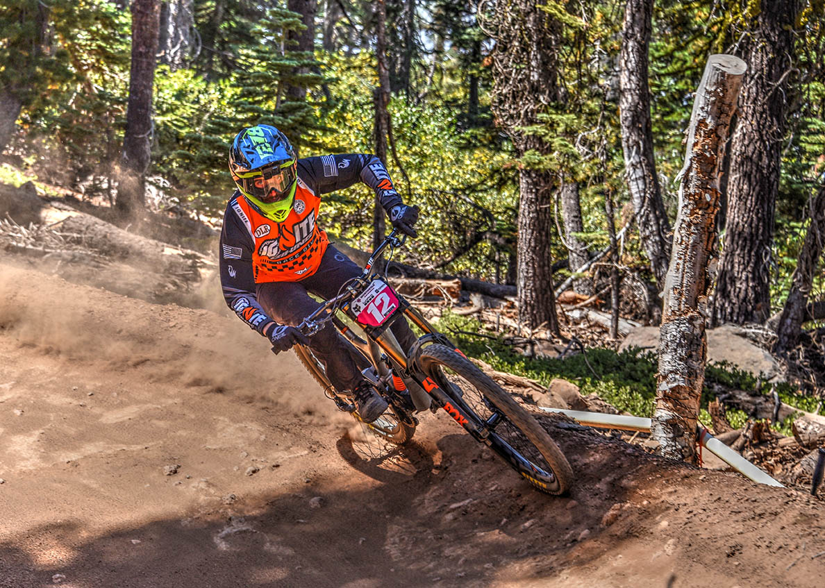 A downhill mountain biker from the IGnite Biking team racing at Northstar California Bike Park, wearing a custom MTB jersey.