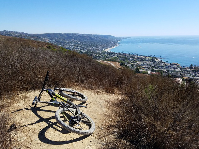 A scenic view of mountain bike trails winding through the rolling hills of Laguna Coast Wilderness Park, surrounded by coastal sage scrub and open sky.