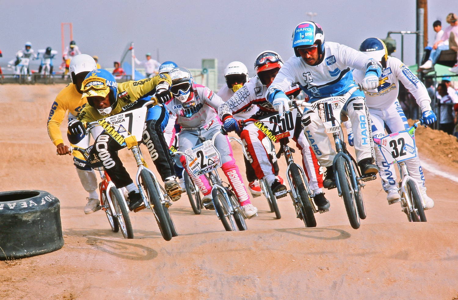 BMX riders racing in colorful jerseys and BMX pants, riding Haro bikes in a retro 1990s race.