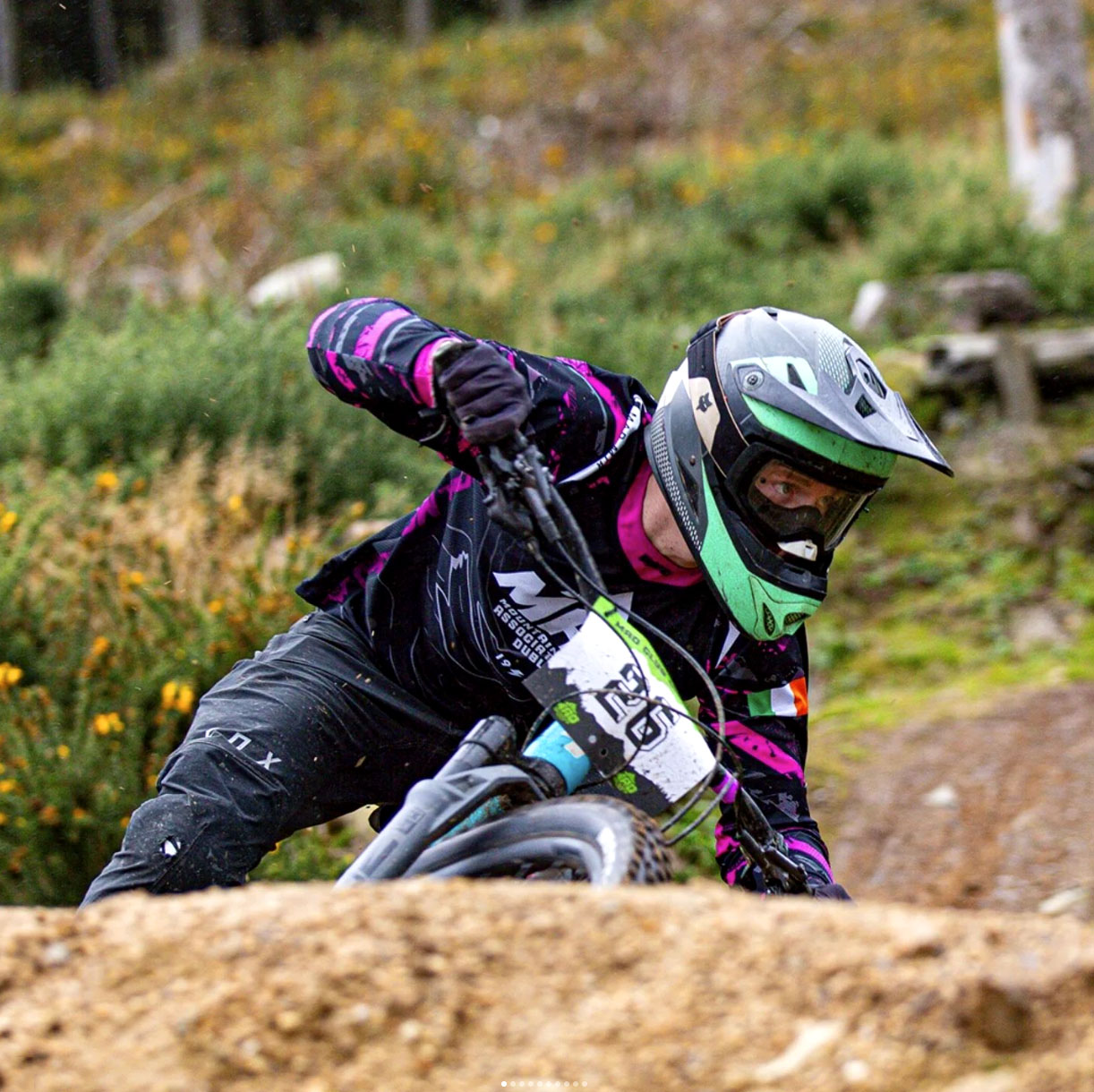 Team MAD MTB rider racing on trails, wearing the pink version of their custom jersey with abstract patterns and personalized details.